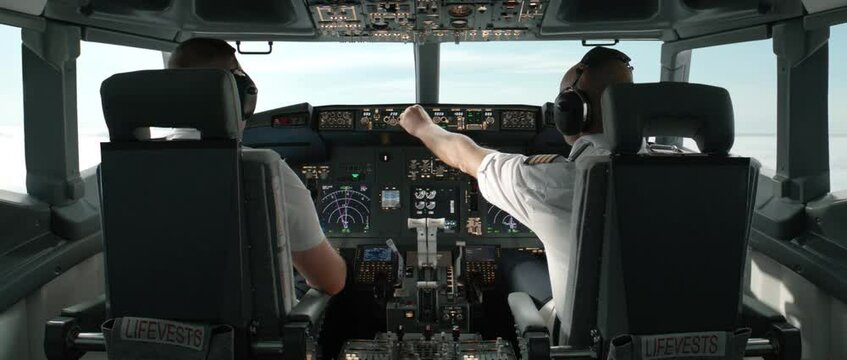 Commercial aircraft pilots adjusting flight parameters of the plane during the flight at high altitude. View from inside the cabin. Real aircraft, daytime shot