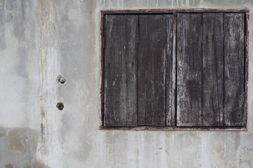 Wooden windows were installed on the walls of concrete houses and were in disrepair as the houses were built for a long time. The walls of the concrete house are old and stained.