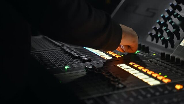 close-up of a male hand on a mixing console. sound engineer works in the club. concert at the stadium. backstage of the event. sound engineer adjusts the volume level. monitors screens in the studio