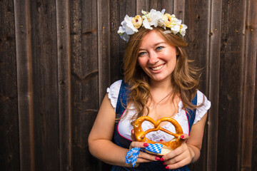 Beautiful woman with pretzel in a traditional bavarian dirndl Oktoberfest.