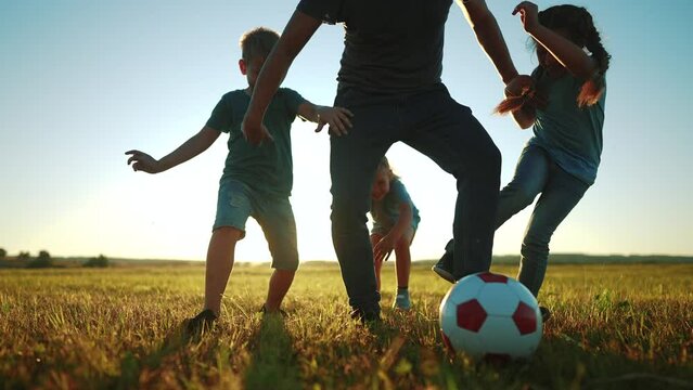 happy family playing a soccer in the park. group of children in nature playing ball with father silhouette park. happy family kid dream concept. funny kids playing ball on grass sunlight in summer