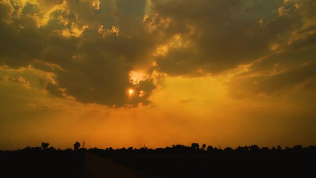 Beautiful shot of sunset behind clouds with silver lining and rays in rural area of Pakistan
