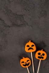 Pumpkin jelly candies on a wooden stick. Halloween. Dark background. Top view. Copy space