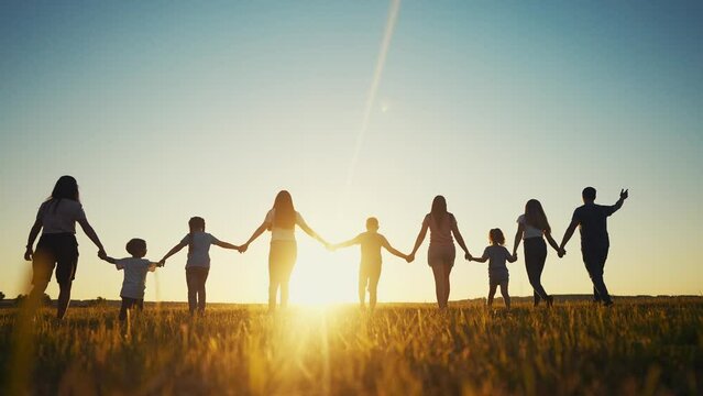 community large family in the park. a large group of people holding hands walking silhouette on nature sunset in the park. big family kid dream concept. people in the park. large family lifestyle