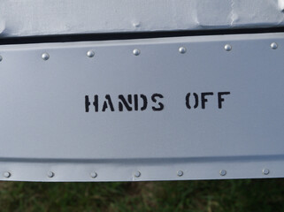 Signe "hands off" sur une plaque de métal rivetée (volet d'aile d'avion)