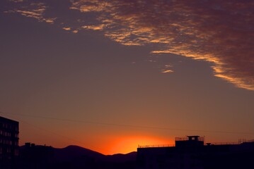 Sunrise from behind the mountains against the backdrop of urban new buildings
