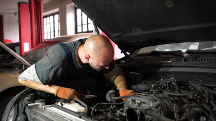 Fototapeta na wymiar Auto mechanic repairs SUV engine. auto repair station. automobile