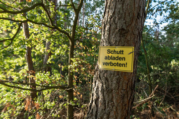 Ein Schild Schutt abladen verboten an einem Baum