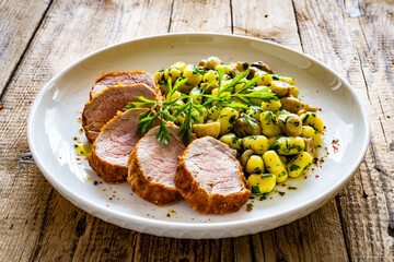Fried pork loin with gnocchi and mushrooms on wooden table
