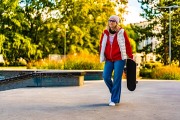 Young woman walking with skateboard in skate park
