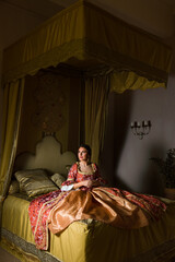 Renaissance woman on golden canopy bed © Anneke