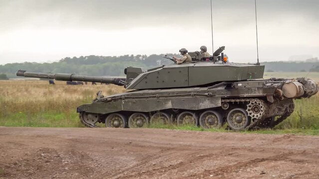 close up of a british army challenger ii 2 FV4034 main battle tank crossing a track in to woodland in action on a military exercise