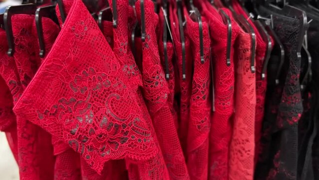 Red lace women's panties hanging in a row on hangers in a lingerie store. Closeup