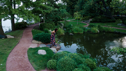 Obraz premium black woman walking around happy and cheerful in an outdoor Chicago park during the day. she is smiling while enjoying all of nature in a beautiful summer dress.
