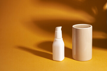 A cosmetic white bottle with a dispenser stands next to the podium for your product, a shadow on the surface. Skin care. A container for cosmetic products for skin care. High quality photo
