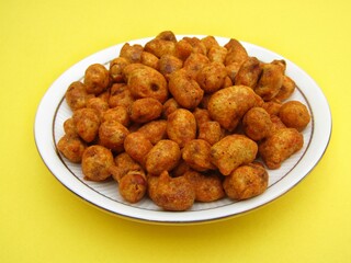 Indian snack food Masala peanuts in a plate on yellow background 