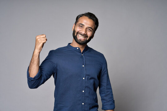 Happy Excited Rich Successful Indian Professional Business Man Leader Investor Executive Winner Raising Fist Isolated On Gray Background Celebrating Success Victory, Rejoicing Work Achievements.