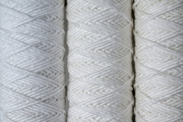 Three coils of white thread for sewing, close-up.