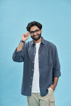 Smiling Confident Young Arab Man Standing Isolated On Blue Background. Happy Handsome Arabic Ethnic Guy Professional Worker Wearing Glasses Looking At Camera Posing For Vertical Portrait.