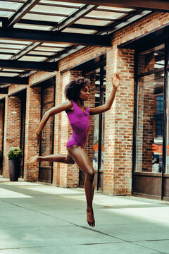 ballerina modern dancer in leotard outdoors in urban street sidewalk brick wall