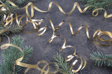 Christmas composition of fir branches and a gold ribbon on a black oil with gold embossing background.