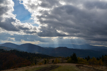 Scenic autumn mountain landscape with rays of light through cloudy sky. Carpathian Mountains, Ukraine