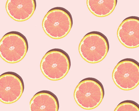 Colorful grapefruit pattern on pastel light pink background. Minimalistic fruit concept. Creative summer nature composition.