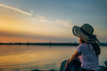 close-up portrait of a woman from the back in a summer hat at sunset on the sea, ocean in travel