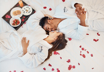 Young couple love on bed, with flowers and healthy snack on tray while on holiday. Man and woman,...