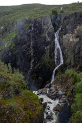 Wonderful landscapes in Norway. Vestland. Beautiful scenery of Voringfossen waterfall in the Mabodalen valley on the Hardanger scenic route. Mountains, trees in background. Cloudy day. Selective focus