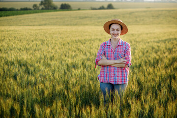 Portrait female-farmer in a straw hat and checkered shirt in wheat field.