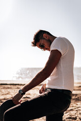 Fototapeta na wymiar Hombre joven modelo con camisa, gorro y gafas de sol en una playa