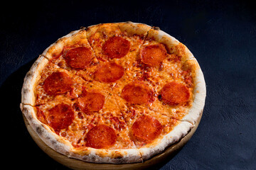 Pizza with tomato sauce, mozzarella, salami on black background. View from above, copy space