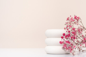 White porous gypsum for podium cosmetic products on a beige background with gypsophila pink flowers eco. Mockup empty template horizontal