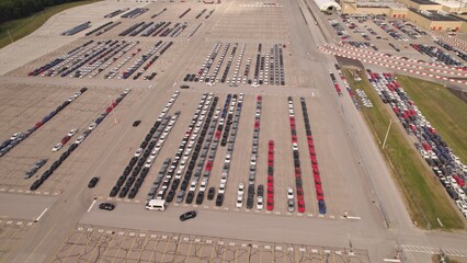 New hybrid EV cars stock parking. Aerial of parking lot of brand new cars for sale and transportation at manufacturer plant, automobile industry. Low carbon footprint electric vehicles from conveyor.