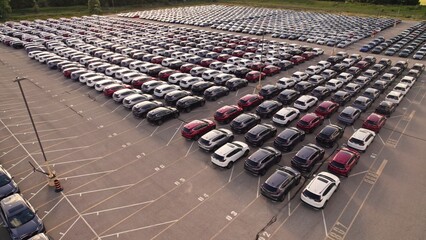Aerial view of car storage or parking lot new unsold EV cars. Vehicle automaker and manufacturer parking facility. Low carbon footprint EV electric cars are ready for further distribution. © desertsands