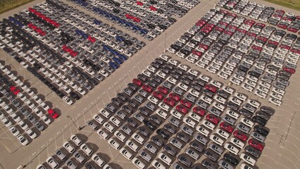 Aerial view of car storage or parking lot new unsold EV cars. Vehicle automaker and manufacturer...