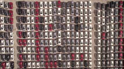 New cars located at the factory parking lot aerial view at golden hour. Car manufactory parking area for a new hybrid EV. High tech green electric vehicles sorted after industrial production conveyor. © desertsands