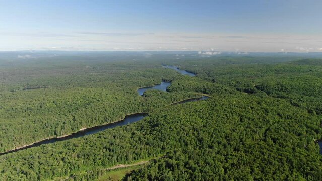 High aerial through low clouds above forested lakes in Mont Tremblant, Quebec Canada in summer