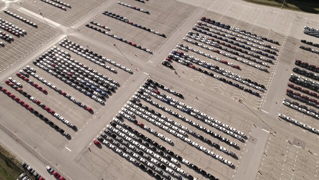 Aerial view of car storage or parking lot new unsold EV cars. Vehicle automaker and manufacturer parking facility. Low carbon footprint EV electric cars are ready for further distribution.