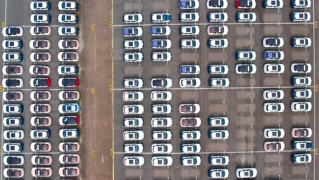 Drones flying over of many vehicles at parking lots. new cars lined up for import and export. automotive industry. 4k stock footage
