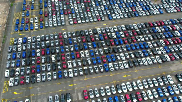 Drones is flying over a lot of cars parked in a automotive factory. new cars lined up for import and export. automobile industry. 4K
