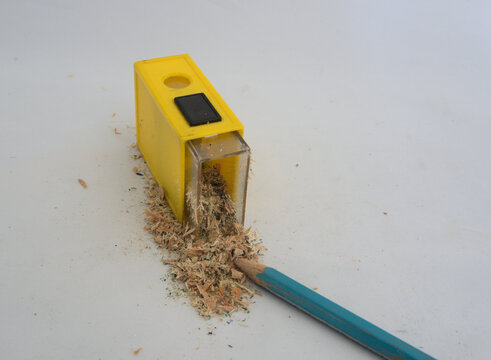 Hand held pencil sharpener spilling the wood flakesfrom a recent sharpening.