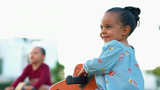 Ni&ntilde;a feliz en un caballo de madera jugando en el parque disfrutando y viviendo alegre divertida al aire libre latina morena en un hermoso atardecer