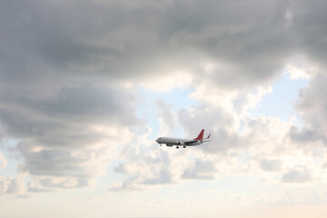 Modern white airplane flying in sky with clouds