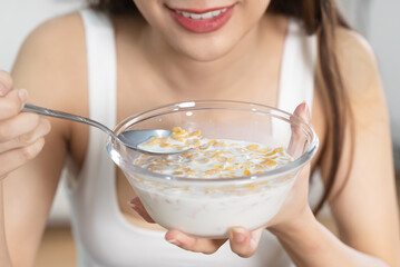 woman eating a bowl of cereal with milk as breakfast in morning