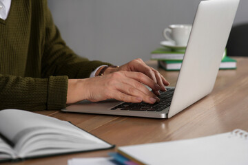 Woman with modern laptop learning at table indoors, closeup
