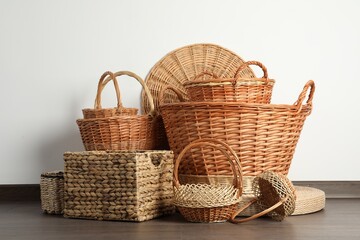 Many different wicker baskets made of natural material on floor near light wall