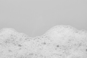 Fototapeta premium Fluffy bath foam on light background, top view. Space for text