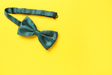Stylish green satin bow tie on yellow background, top view. Space for text